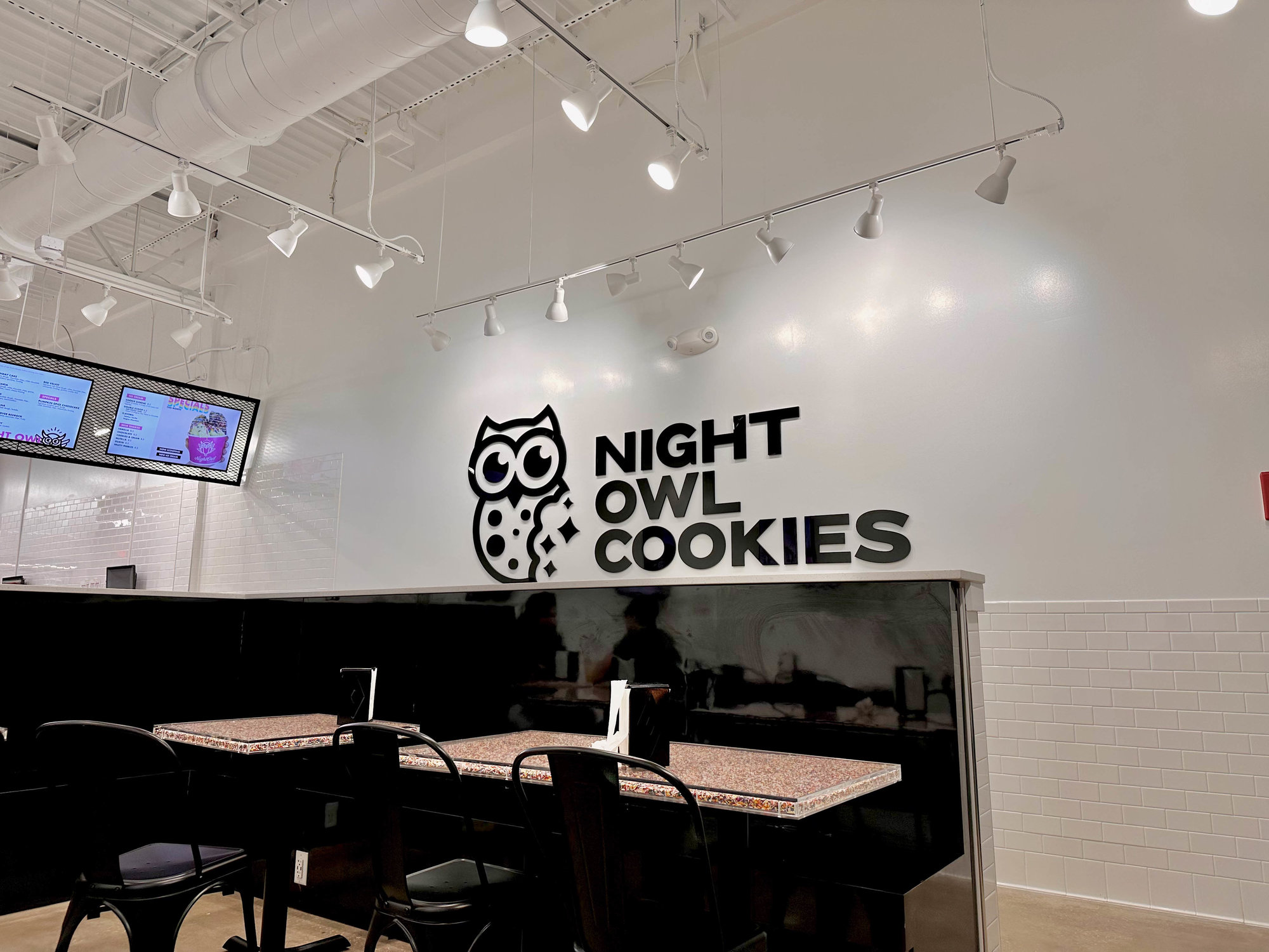 white wall with black night owl cookies sign
